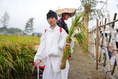 刈り取った稲を持つ、田男姿のこどもです。